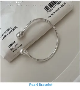 Detail of silver S925 open cuff bracelet with dual white pearls on a display bag