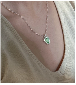 Détail du collier en argent S925 avec pierre précieuse cœur vert sur pull beige