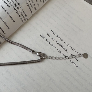 Elegant S925 sterling silver flat snake bone chain necklace displayed on a vintage book