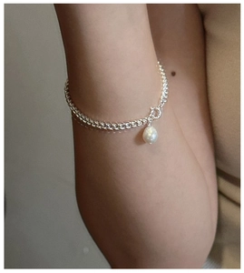 Détail d'un bracelet en argent S925 avec perle baroque porté au poignet d'une femme