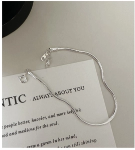 Detailed macro view of S925 silver snake chain bracelet featuring a delicate white pearl pendant