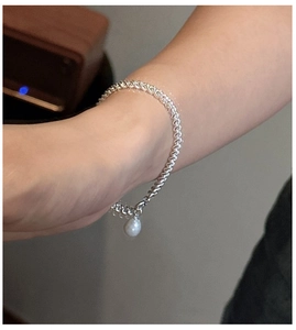 Vue détaillée du bracelet en argent torsadé avec un pendentif perle blanche sur le poignet