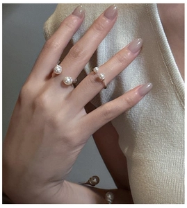 Detailed close-up of adjustable gold pearl rings on a warm knitted background