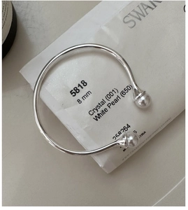 Detail shot of a silver open bangle featuring two elegant 8mm white pearls on each end
