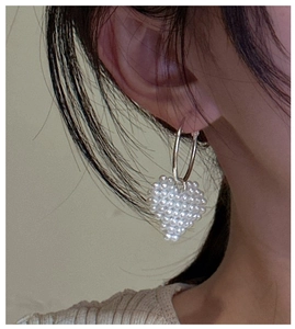 Détail de boucles d'oreilles en argent avec pendentifs cœurs en perles tressées
