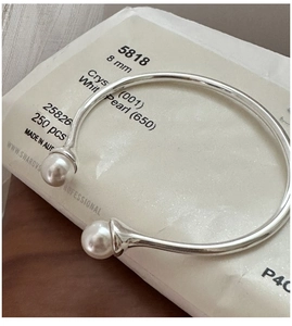 Macro detail of 8mm white pearl on minimalist S925 sterling silver open bangle bracelet