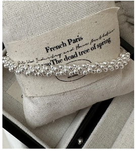Macro shot of S925 sterling silver beaded rope bracelet on a textured linen pillow