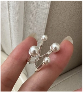 Detail of S925 silver ring featuring four white pearls in a minimalist cross-spiral design