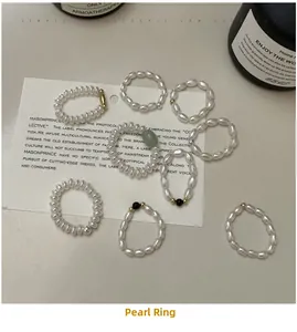 Dettaglio di anelli di perle in argento S925 e cristallo su un cartoncino minimalista