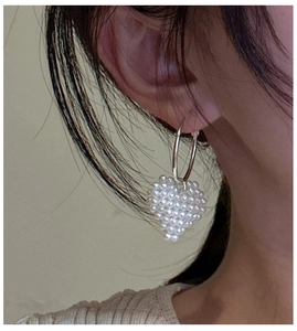 Détails de cœurs en perles tressées sur créoles en argent portées par un mannequin