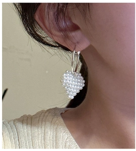 Gros plan de boucles d'oreilles cœur en perles avec un design élégant en argent