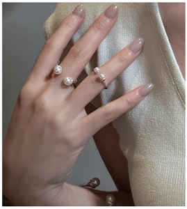Detail of silver S925 rings featuring glossy white pearls on a model hand