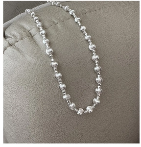 Macro detail of silver S925 beaded chain necklace with matte finish texture