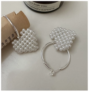 Détail de boucles d'oreilles créoles en argent S925 avec pendentifs cœur en perles
