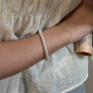 Elegant S925 sterling silver triple-strand beaded bracelet on model with soft background