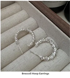 Detail of S925 sterling silver C-shaped earrings featuring textured sparkling finish