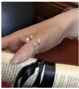 Detailed view of an adjustable silver pearl ring with four staggered white pearls
