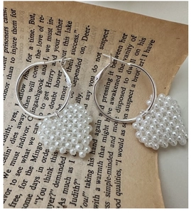 Détail de pendentifs cœur en perles tressées sur boucles d'oreilles en argent pur