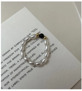 Vista dettagliata di un anello fatto a mano con perle bianche e nere su cartoncino