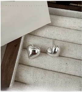 Macro view of polished S925 sterling silver heart-shaped stud earrings in a jewelry box