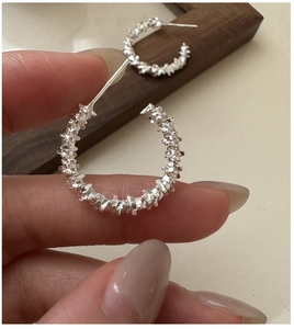 Detail shot of S925 silver C-shape earrings with a textured industrial finish