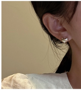 Close-up of minimalist S925 sterling silver heart stud earring worn by a model