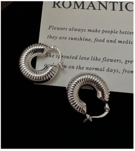 Detailed view of silver hoop earrings with threaded texture on a minimalist card