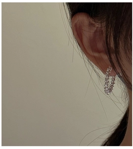 Detail of silver hoop earrings with pave-set rhinestones worn on ear, side view