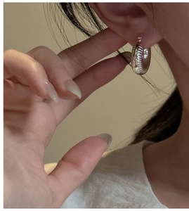 Detail view of S925 sterling silver hoop earrings with croissant textured design on ear