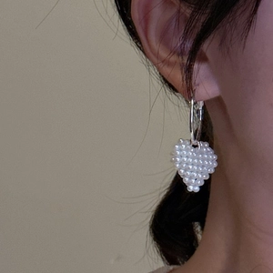 Boucles d'oreilles cœur en perles tressées portées par un mannequin au style épuré