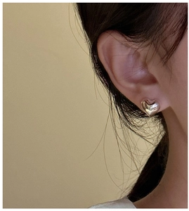 Close-up of minimalist S925 sterling silver heart stud earrings worn on the ear