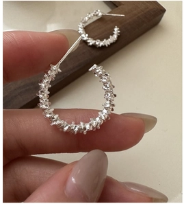 Detailed view of S925 silver C-shape earrings with unique textured finish on hand