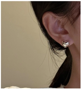 Close-up of minimalist S925 sterling silver heart stud earrings worn by a model