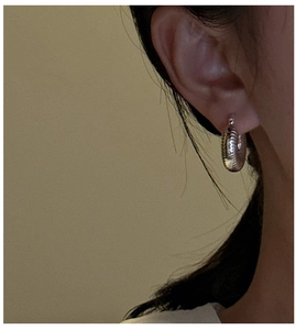 Detailed view of silver hoop earrings with textured wavy pattern on the earlobe