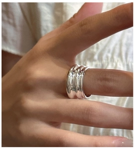 Détail d'une bague large en argent S925 avec texture à trois vagues portée sur la main