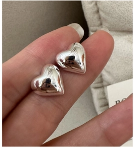 Macro shot of minimalist S925 sterling silver heart studs with polished mirror finish