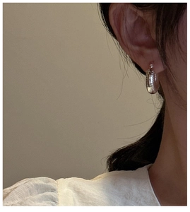 Classic S925 sterling silver hoop earrings with wave texture worn by a model