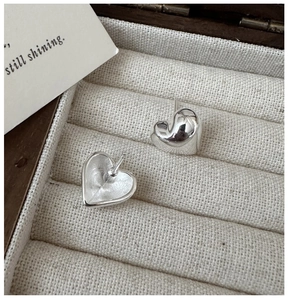 Macro view of polished heart stud earrings in a beige velvet jewelry gift box