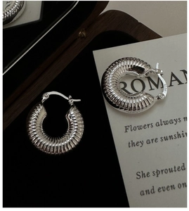 Macro detail of S925 sterling silver croissant hoop earrings with polished spiral texture