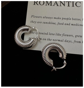 Macro detail of silver S925 sterling silver hoop earrings with spiral ribbed texture