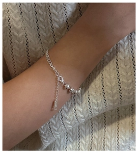 Close-up of S925 sterling silver beaded bracelet worn over beige knitwear texture