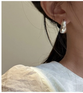 Close-up of polished S925 sterling silver hollow moon drop earring worn by a model