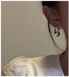 Close-up of minimalist S925 sterling silver hollow moon drop earrings worn by a model