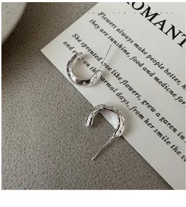 Macro detail of textured C-shape sterling silver earrings with hammer-textured finish