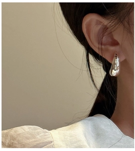 Detailed close-up of a hollow silver moon earring worn by a model in a minimalist style