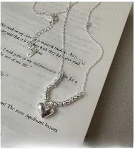 Detail of S925 silver heart necklace with laser beads on a book page background