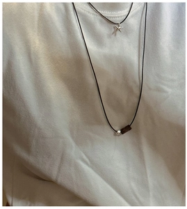 Close-up of double-layered necklace set with star and wood tube pendant on black cord