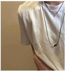 Detail of layered S925 silver star pendant and wood bead necklaces on a white T-shirt
