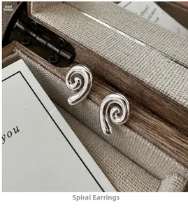 Macro shot of silver S925 spiral earrings displayed in a vintage wooden jewelry box