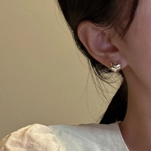 S925 sterling silver heart stud earrings with a polished finish worn by a model